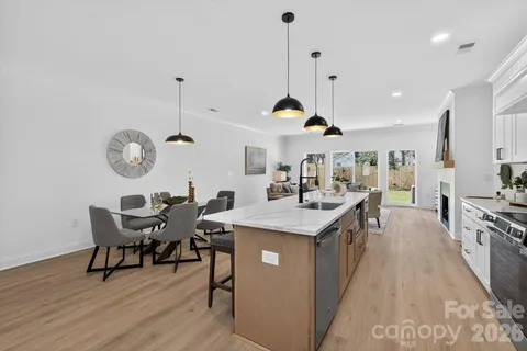 a kitchen with kitchen island stainless steel appliances a table chairs sink and wooden floor