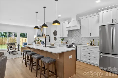 a kitchen with stainless steel appliances granite countertop a sink a stove a refrigerator and island with wooden floor