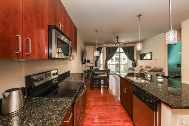 a kitchen with stainless steel appliances granite countertop a stove a sink dishwasher and cabinets with wooden floor
