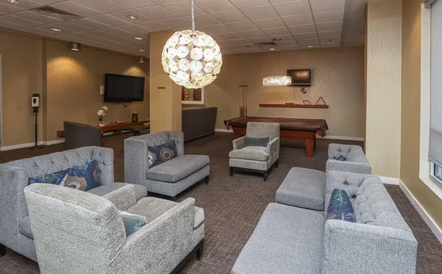 a living room with furniture a chandelier and a flat screen tv
