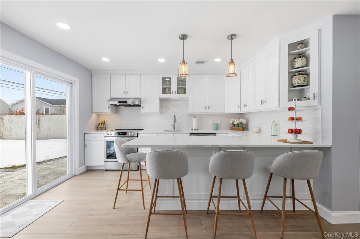 89 Ridge Lane Levittown, NY 11756 - Photo 13 of 44 a kitchen with stainless steel appliances granite countertop a sink a stove a refrigerator cabinets and dining table