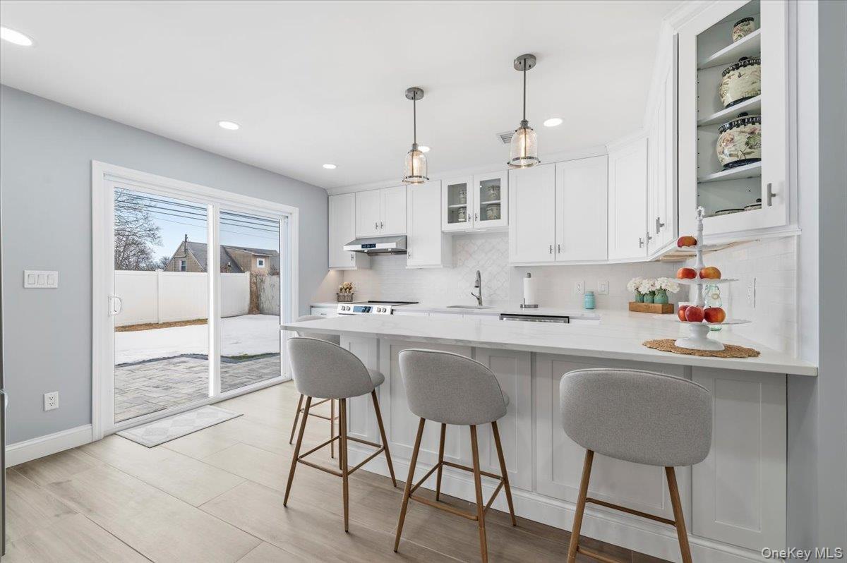 89 Ridge Lane Levittown, NY 11756 - Photo 16 of 44 a kitchen with stainless steel appliances granite countertop a sink a stove a refrigerator and island with wooden floor