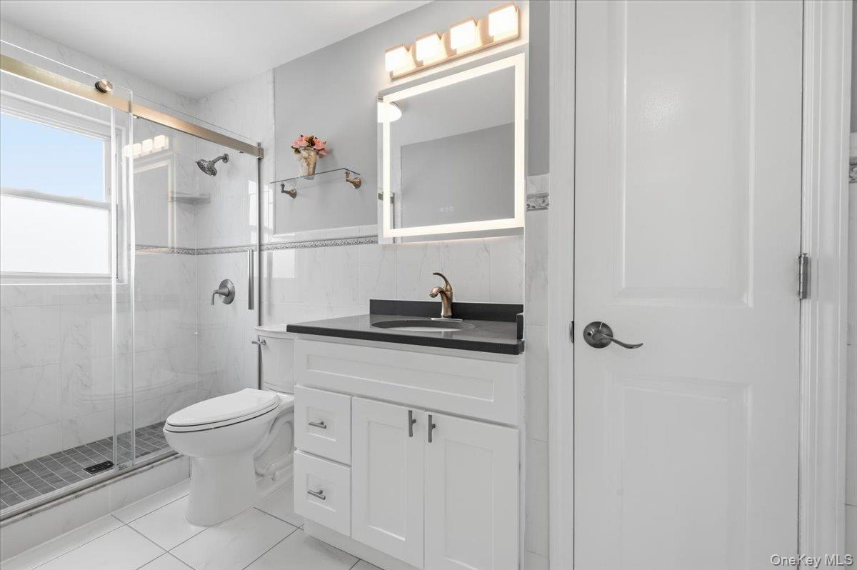 89 Ridge Lane Levittown, NY 11756 - Photo 24 of 44 a bathroom with a granite countertop sink a toilet and a mirror