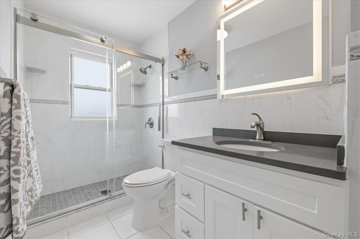 89 Ridge Lane Levittown, NY 11756 - Photo 25 of 44 a bathroom with a granite countertop sink a toilet and shower
