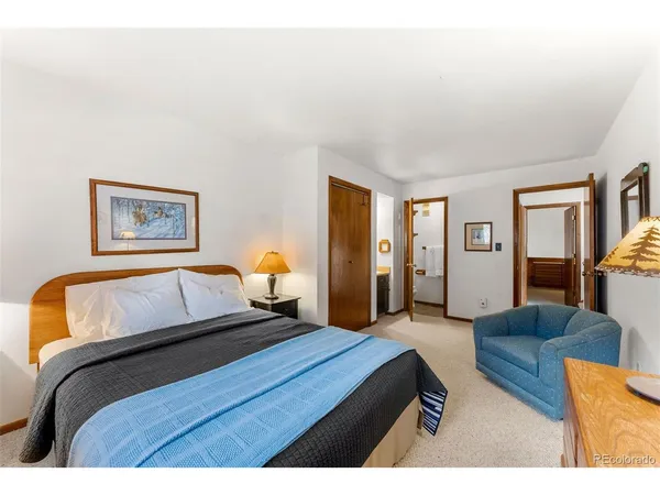a bedroom with a large bed couch and two windows