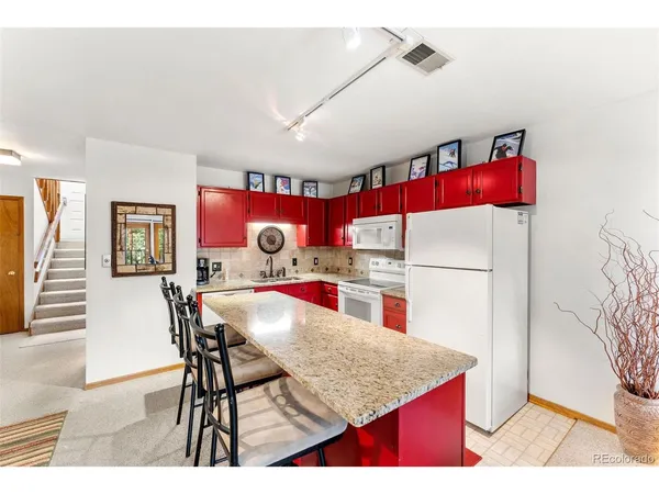 a kitchen with stainless steel appliances kitchen island granite countertop a table chairs and a refrigerator
