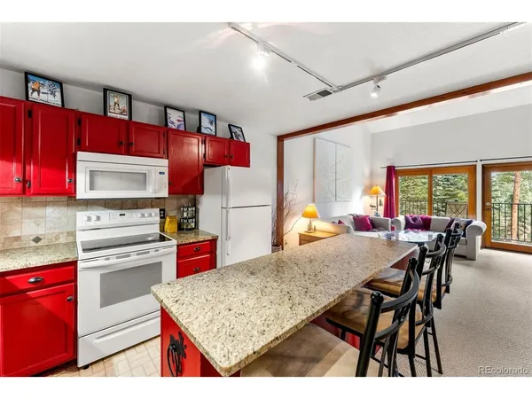 a kitchen with stainless steel appliances granite countertop a stove top oven a refrigerator and cabinets
