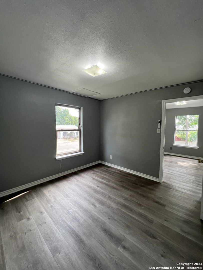 1723 West Mayfield Boulevard, Unit 4 San Antonio, TX 78211 - Photo 11 of 14 an empty room with wooden floor and windows