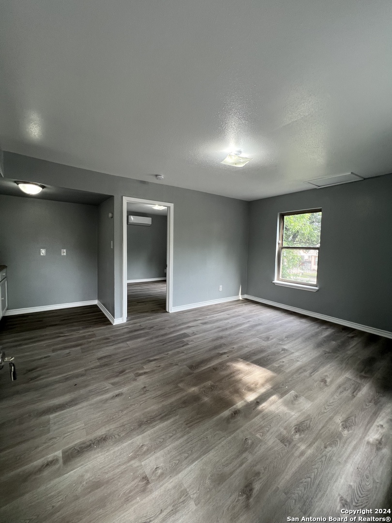 1723 West Mayfield Boulevard, Unit 4 San Antonio, TX 78211 - Photo 3 of 14 an empty room with wooden floor and windows