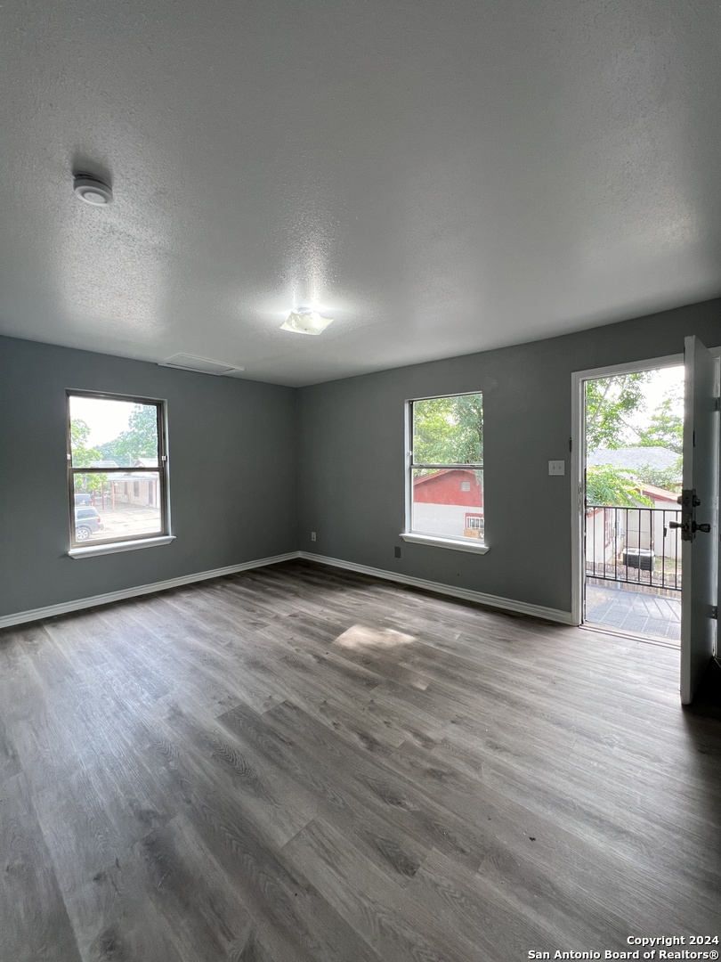 1723 West Mayfield Boulevard, Unit 4 San Antonio, TX 78211 - Photo 7 of 14 an empty room with wooden floor and windows