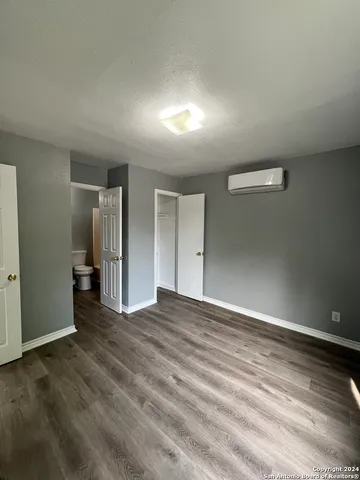 an empty room with wooden floor & windows and bathroom