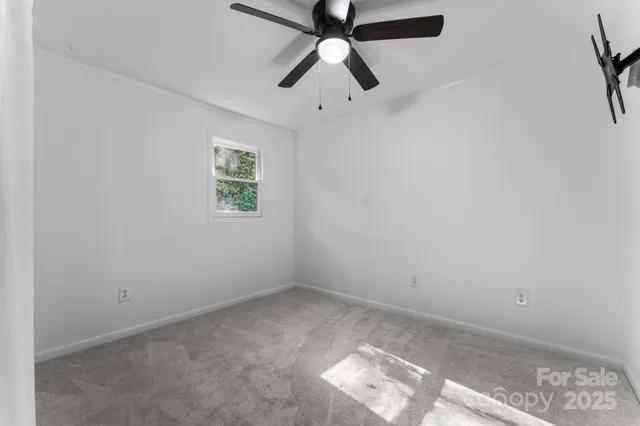 an empty room with a window and a fan