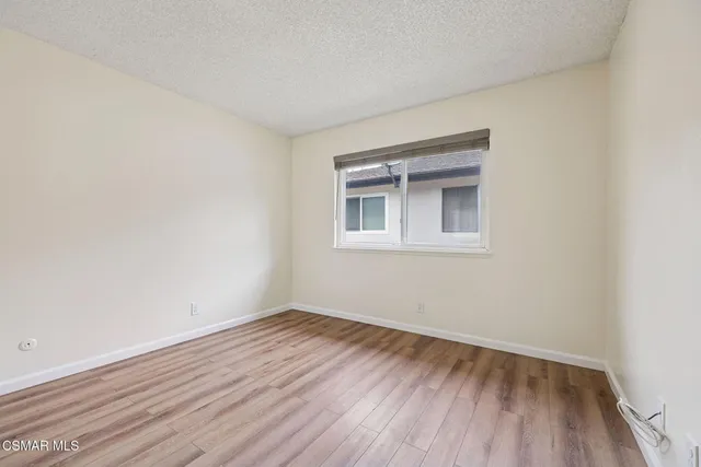 a view of an empty room with wooden floor and a bathroom