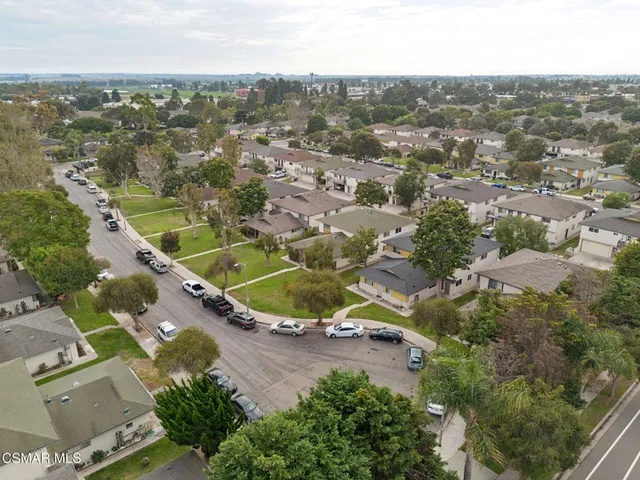 an aerial view of residential houses with outdoor space and trees