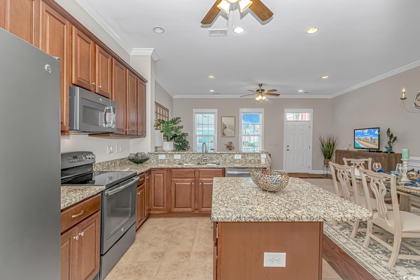 750 Shine Avenue, Unit 750 Myrtle Beach, SC 29577 - Photo 7 of 34 Kitchen with appliances with stainless steel finishes, light stone counters, a peninsula, crown molding, and a center island