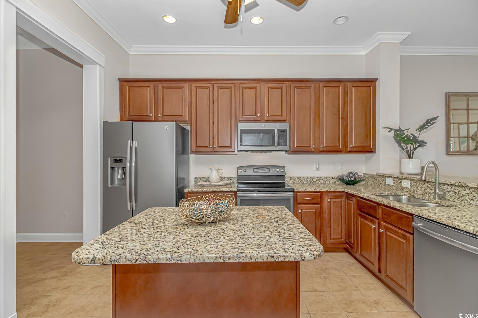 750 Shine Avenue, Unit 750 Myrtle Beach, SC 29577 - Photo 8 of 34 Kitchen featuring brown cabinetry, light stone countertops, appliances with stainless steel finishes, crown molding, and a kitchen island