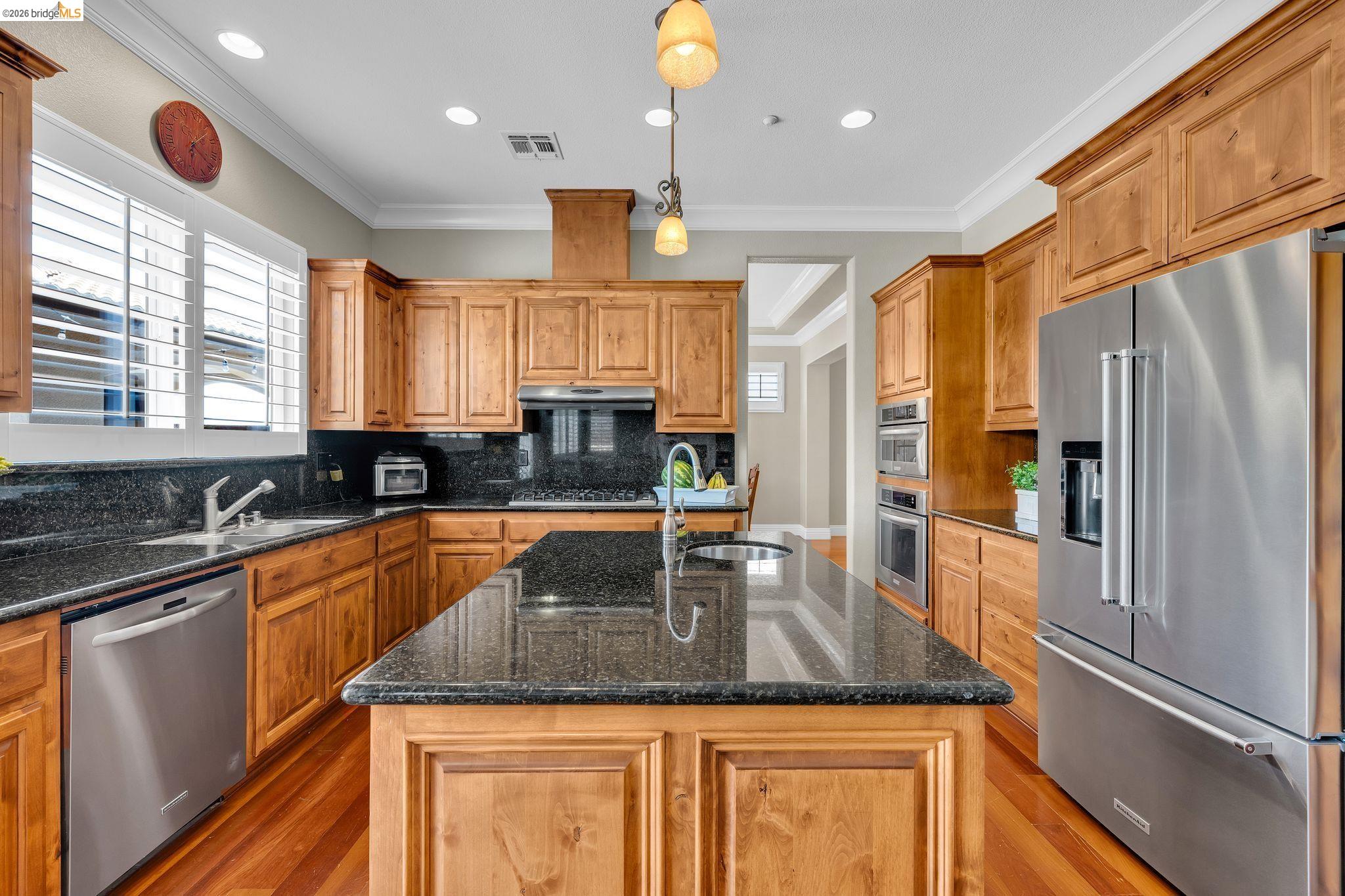 2513 Winged Foot Road Brentwood, CA 94513 - Photo 7 of 45 Kitchen featuring a large central island with a sink, wood-finish cabinetry, granite countertops, stainless steel appliances, and wood-finish flooring