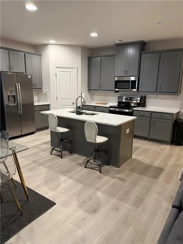 a kitchen with stainless steel appliances kitchen island granite countertop a sink a stove a refrigerator cabinets and chairs