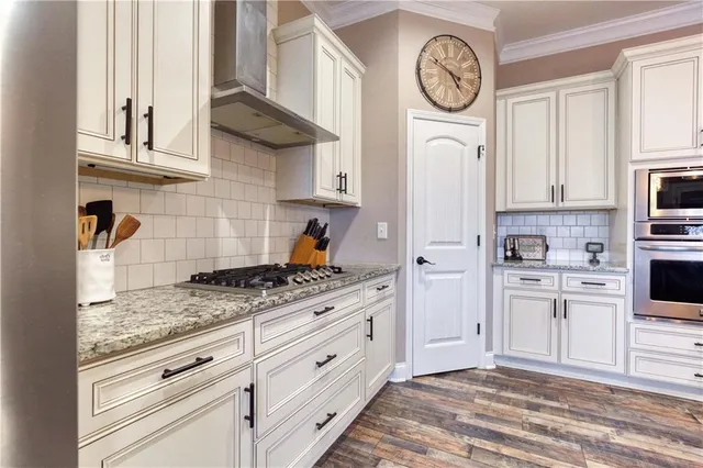 a kitchen with granite countertop a table chairs stainless steel appliances and cabinets