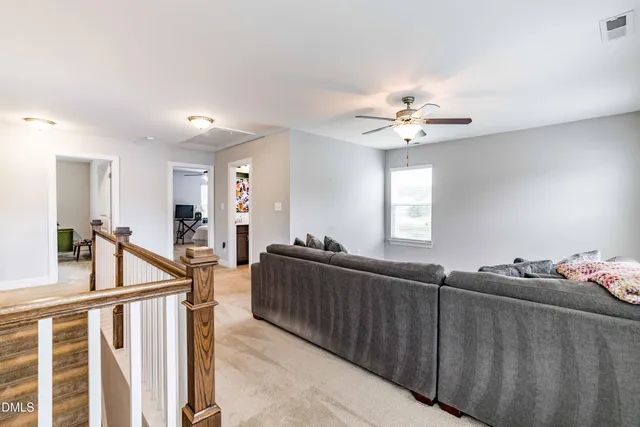 a living room with furniture a chandelier fan and a window