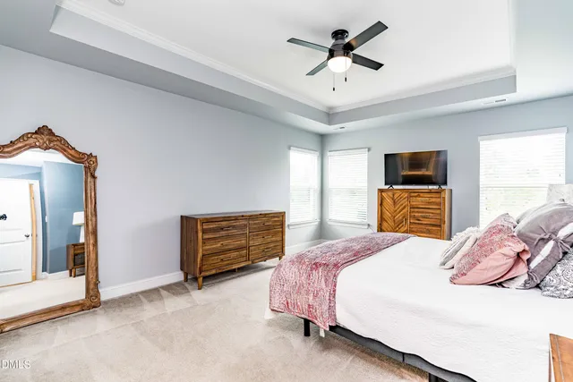 a bedroom with a bed ceiling fan and a dresser