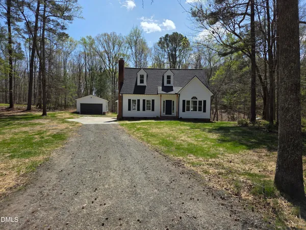 a view of a house with backyard and trees in the background