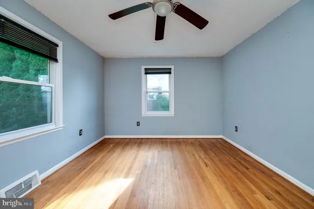 a view of empty room with wooden floor and fan