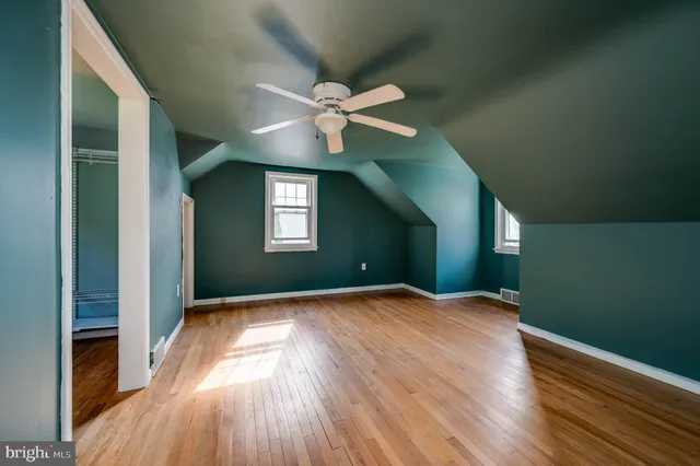 a view of empty room with wooden floor and fan