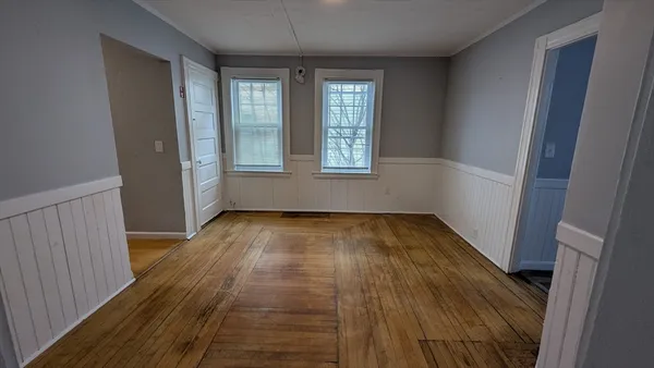 an empty room with wooden floor and windows