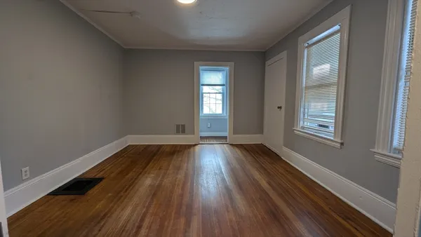 a view of an empty room with wooden floor and a window