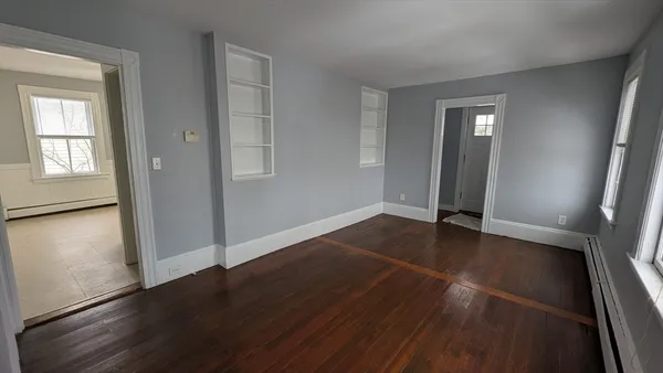 an empty room with wooden floor and windows