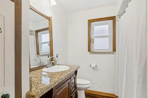 a bathroom with a granite countertop sink toilet and mirror