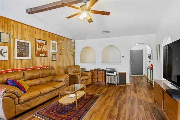 a living room with furniture a flat screen tv and wooden floor