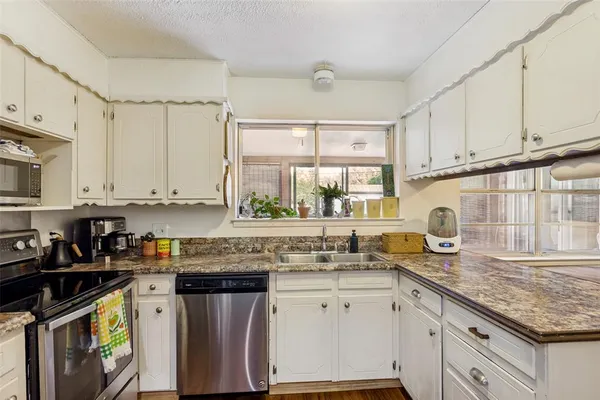 a kitchen with stainless steel appliances granite countertop a sink a stove and cabinets