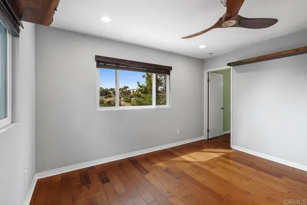 an empty room with wooden floor and a ceiling fan