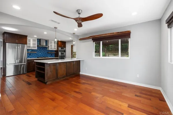 a view of empty room with wooden floor and fan