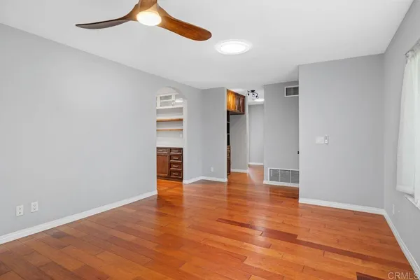 a view of empty room with wooden floor and fan