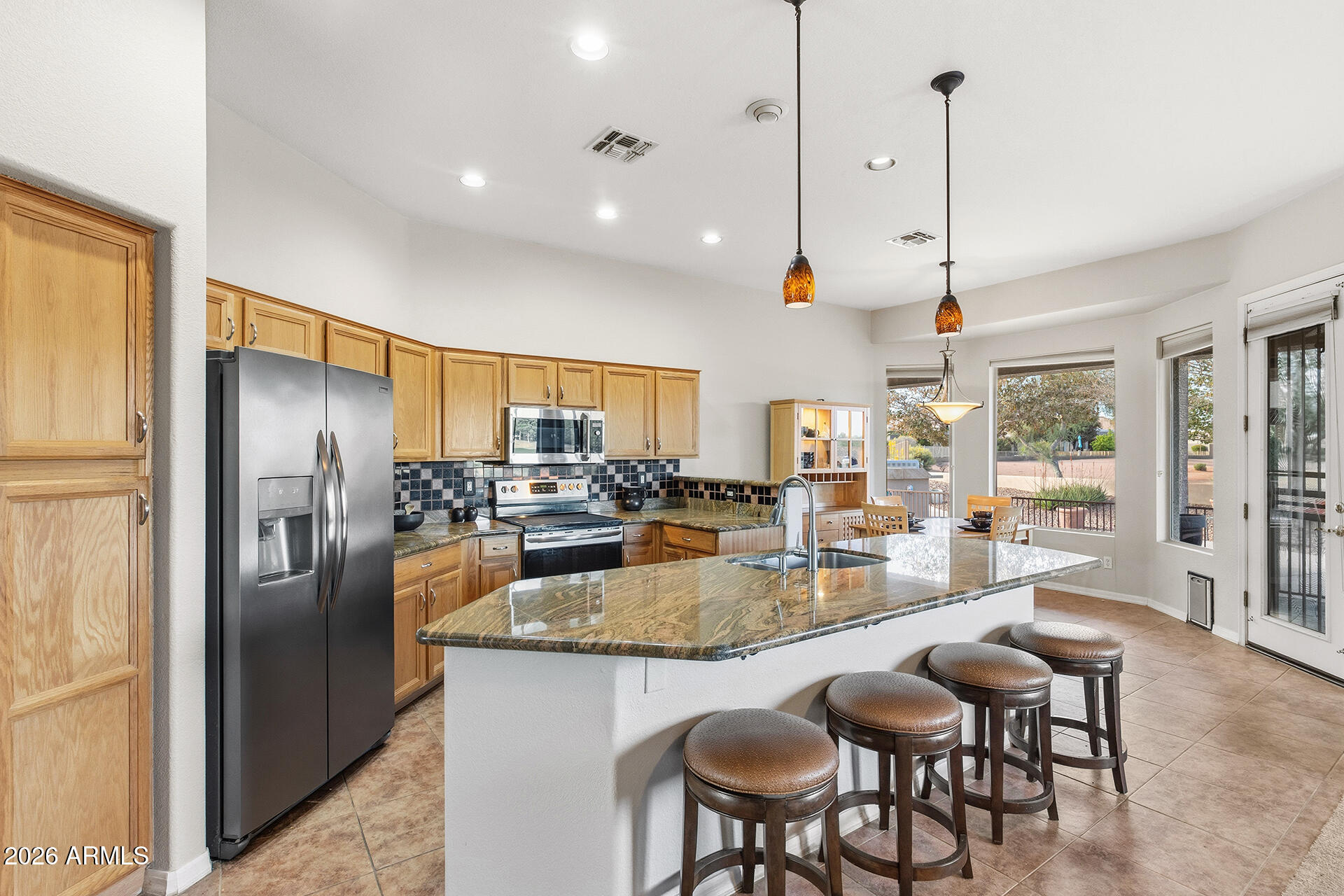 4906 South Verbena Avenue Gilbert, AZ 85298 - Photo 8 of 46 a kitchen with stainless steel appliances granite countertop a refrigerator a stove a sink a dining table and chairs with wooden floor