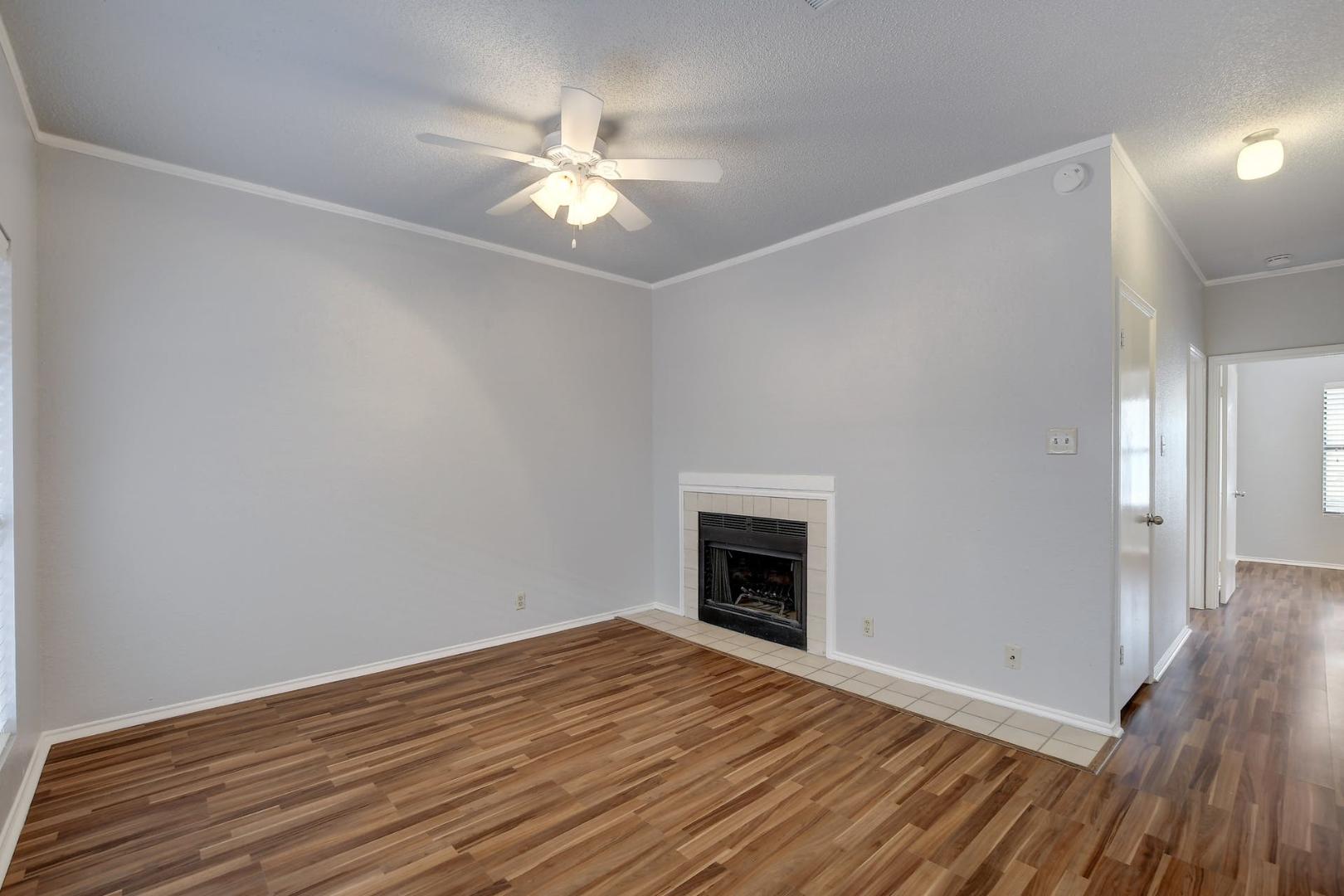 2804 Rio Grande Street, Unit 310 Austin, TX 78705 - Photo 5 of 22 A comforting fireplace provides warmth to this living space with wood flooring and an overhead ceiling fan.