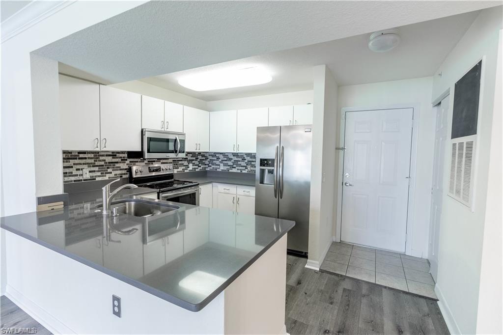 8234 Key Royal Circle, Unit 521 Naples, FL 34119 - Photo 2 of 19 a kitchen with kitchen island a counter top space cabinets and stainless steel appliances