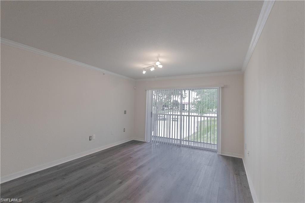 8234 Key Royal Circle, Unit 521 Naples, FL 34119 - Photo 4 of 19 an empty room with wooden floor and windows