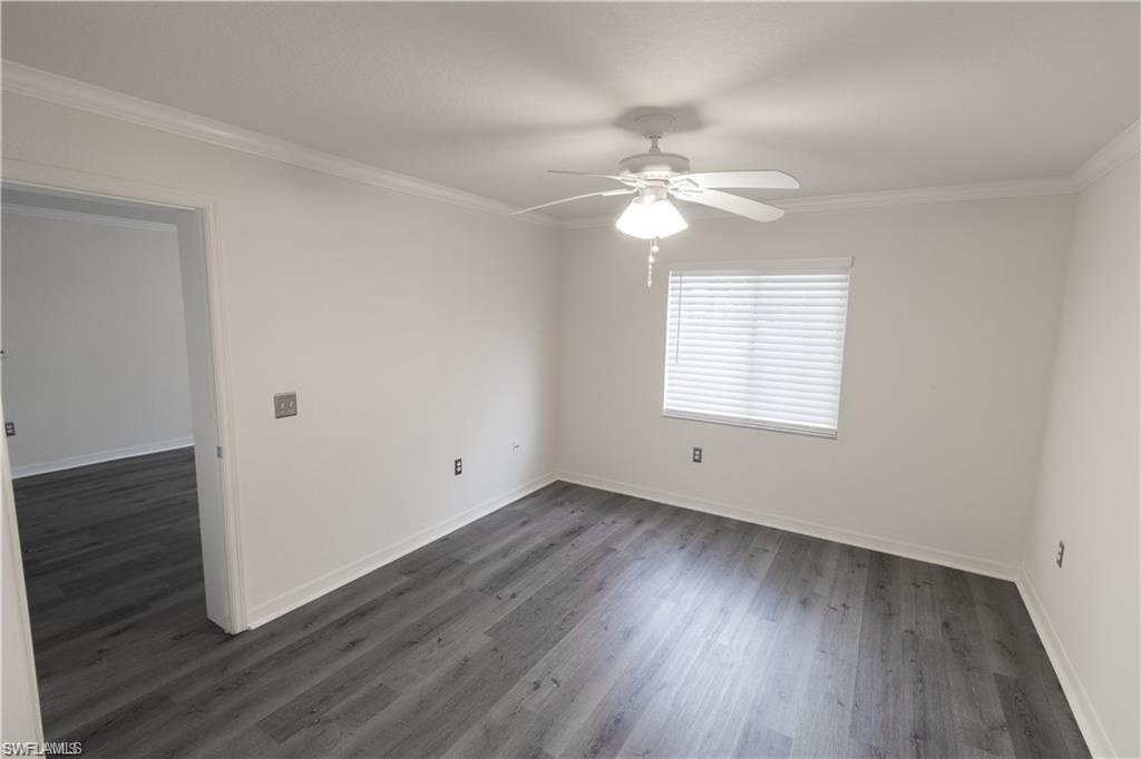 8234 Key Royal Circle, Unit 521 Naples, FL 34119 - Photo 6 of 19 an empty room with wooden floor ceiling fan and windows