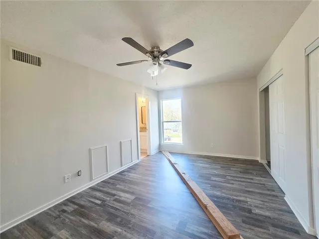 a view of an empty room with window and wooden floor