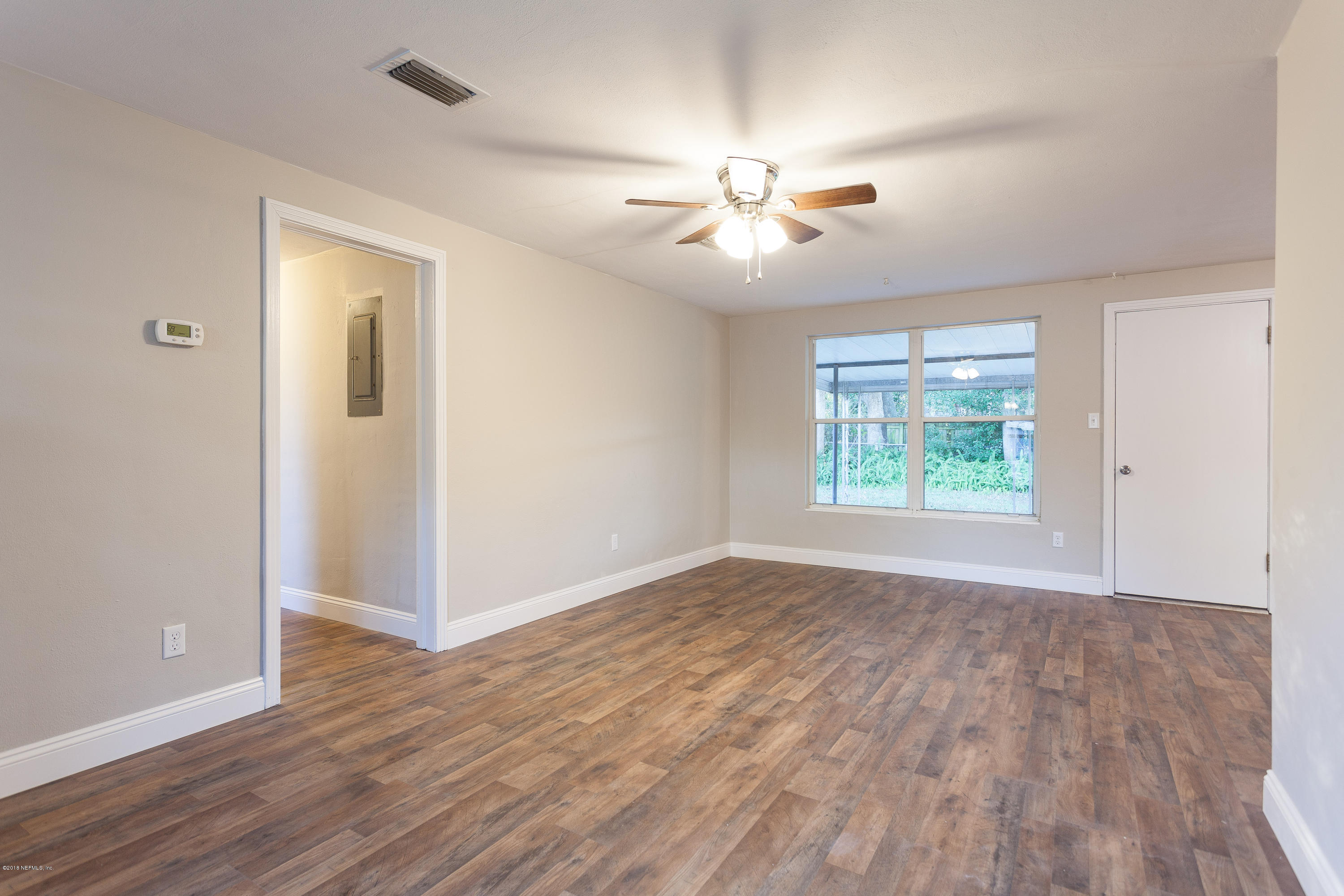 4230 Springwood Road Jacksonville, FL 32207 - Photo 12 of 20 an empty room with wooden floor chandelier fan and windows