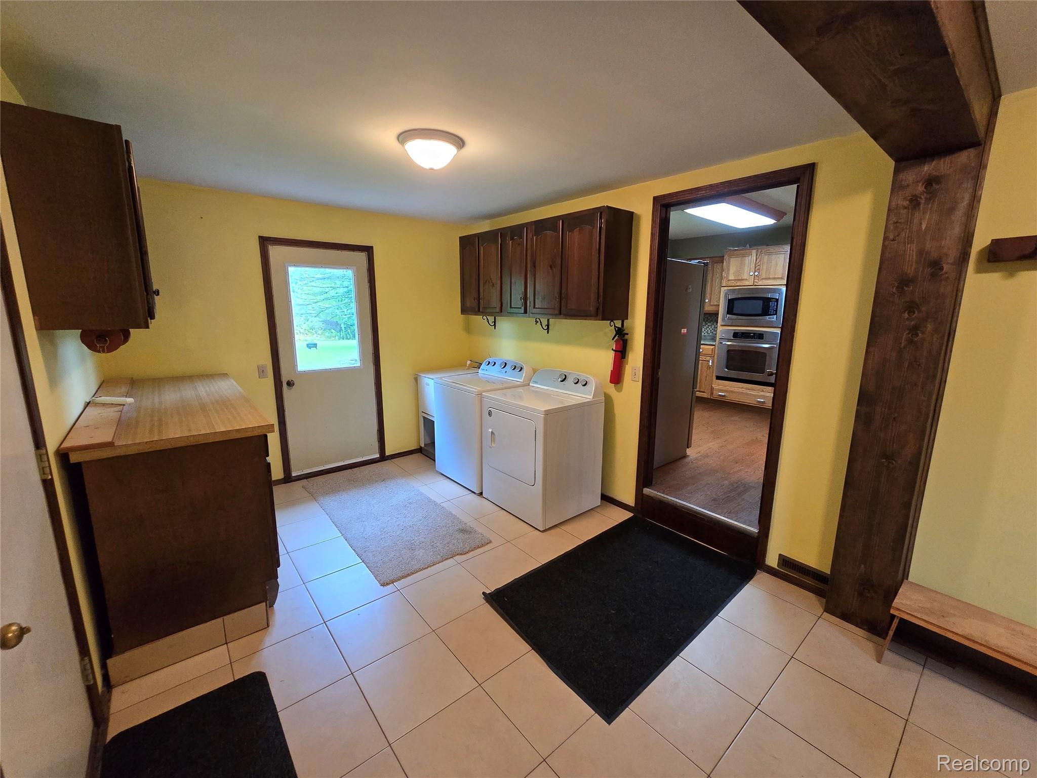 5282 McIntyre Road North Street, MI 48049 - Photo 26 of 53 Tiled flooring, overhead lighting, wood-finish cabinetry, and a door with an exterior view