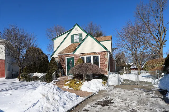 a front view of a house with a yard covered in snow