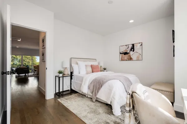 a view of a hallway with wooden floor and a bathroom