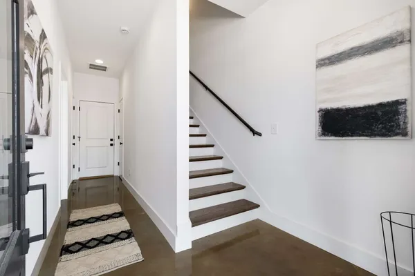 a view of a hallway with front door wooden floor and windows