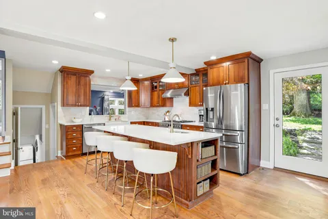 a kitchen with stainless steel appliances kitchen island a table chairs refrigerator and sink