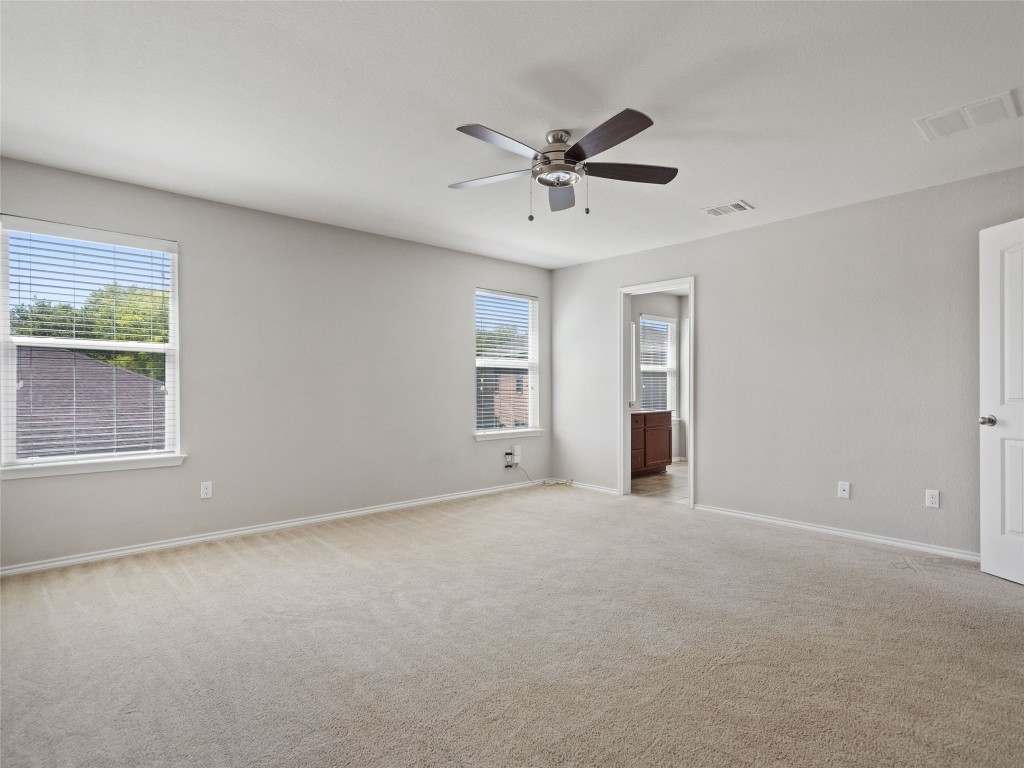 7633 Rio Pass Austin, TX 78724 - Photo 13 of 23 Unfurnished bedroom featuring light carpet, a ceiling fan, and ensuite bath